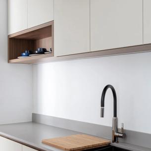 Large white kitchen cabinets, black countertop, silver faucet, wooden cutting board