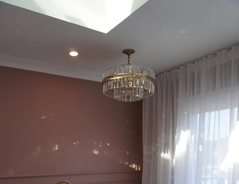 Large white bathtub, brown shower curtain, gold bathroom chandelier, white rug