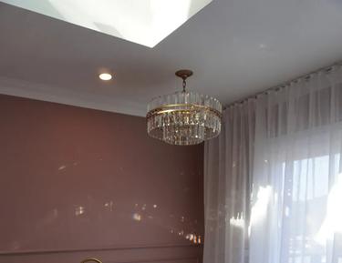 Large white bathtub, brown shower curtain, gold bathroom chandelier, white rug