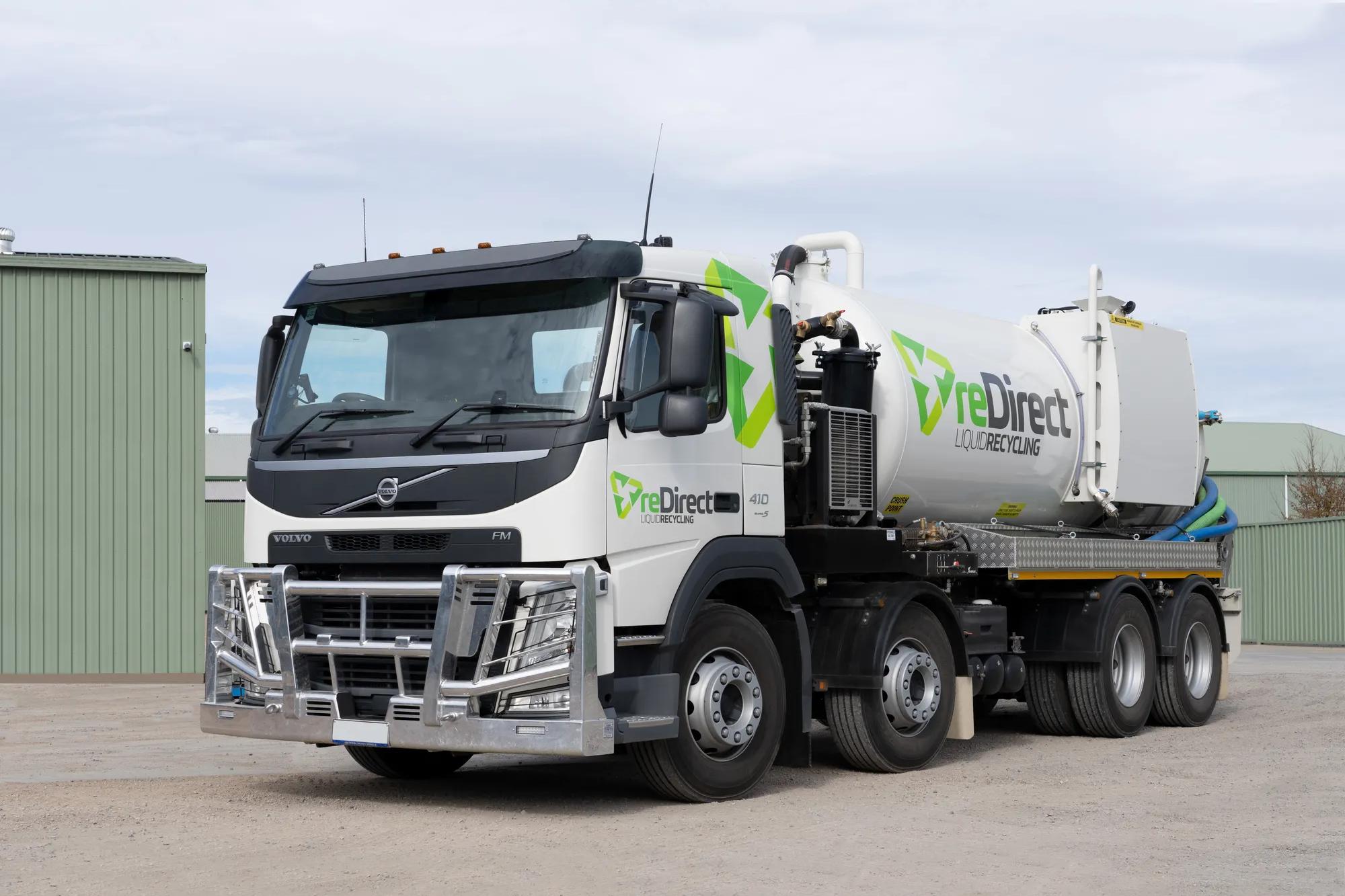 reDirect Liquid Recycling Volvo tanker truck side view outside green shed.