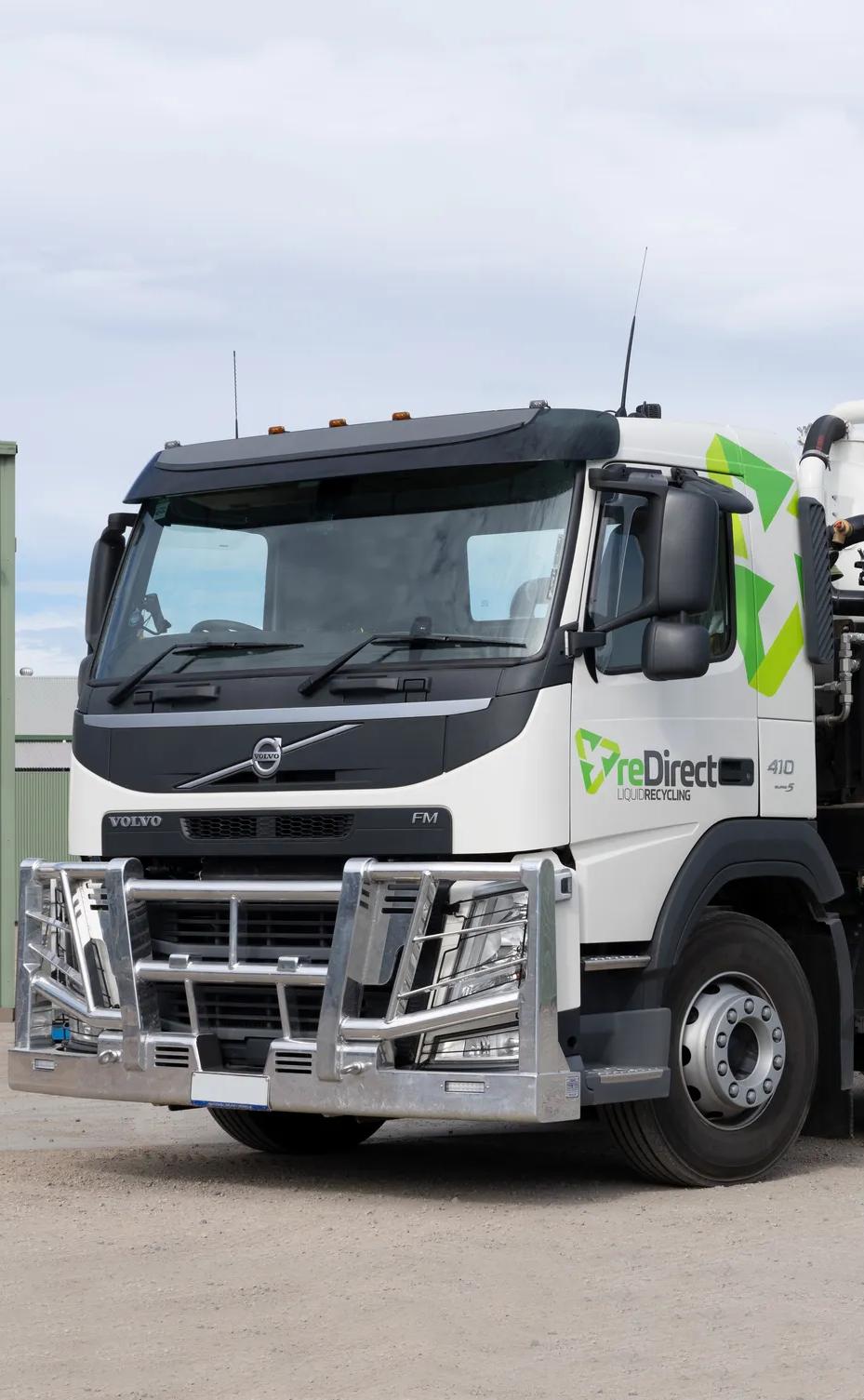 reDirect Liquid Recycling Volvo tanker truck side view outside green shed.