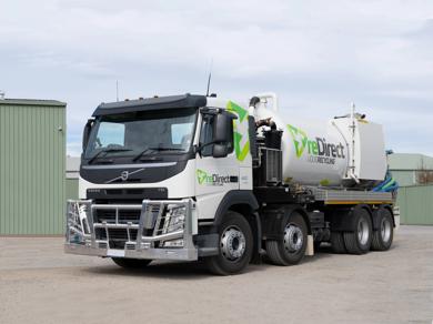 reDirect Liquid Recycling Volvo tanker truck side view outside green shed.