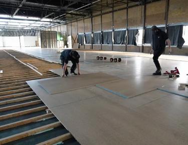 Two men installing STRUCTAflor in an indoor setting