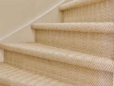 Staircase of beige steps with dark brown carpet